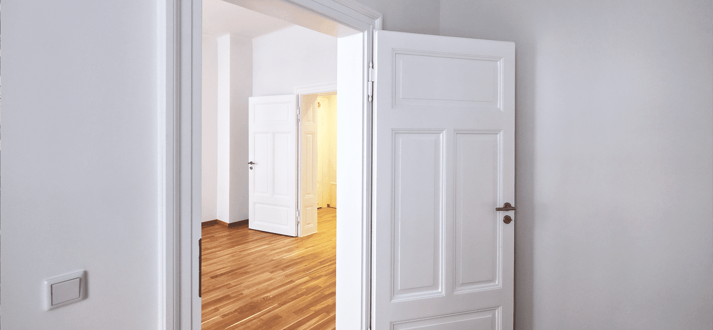 Ein Foto einer lehrstehenden, sanierten Altbauwohnung mit Blick durch mehrere, weiße Türen.
