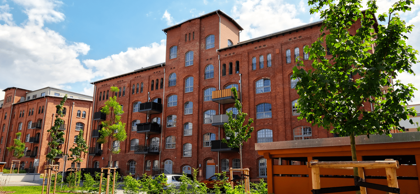 Foto einer sanierten Klinker-Fassade mit zahlreichen Rundbogen-Fenstern und Balkonen.