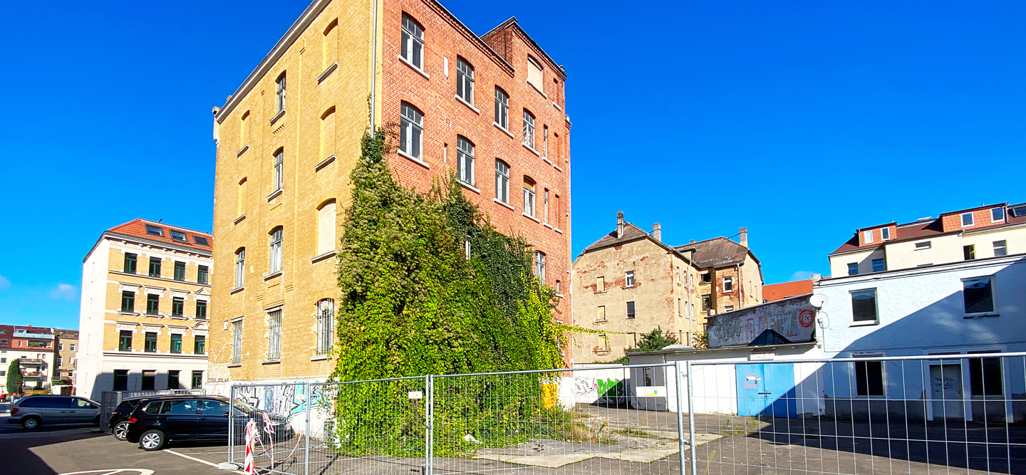 Foto eines freistehenden Backsteingebäudes. Ein Großteil der Fassade ist mit Grün bewachsen. Hier entsteht das Wohncarré Plagwitz.